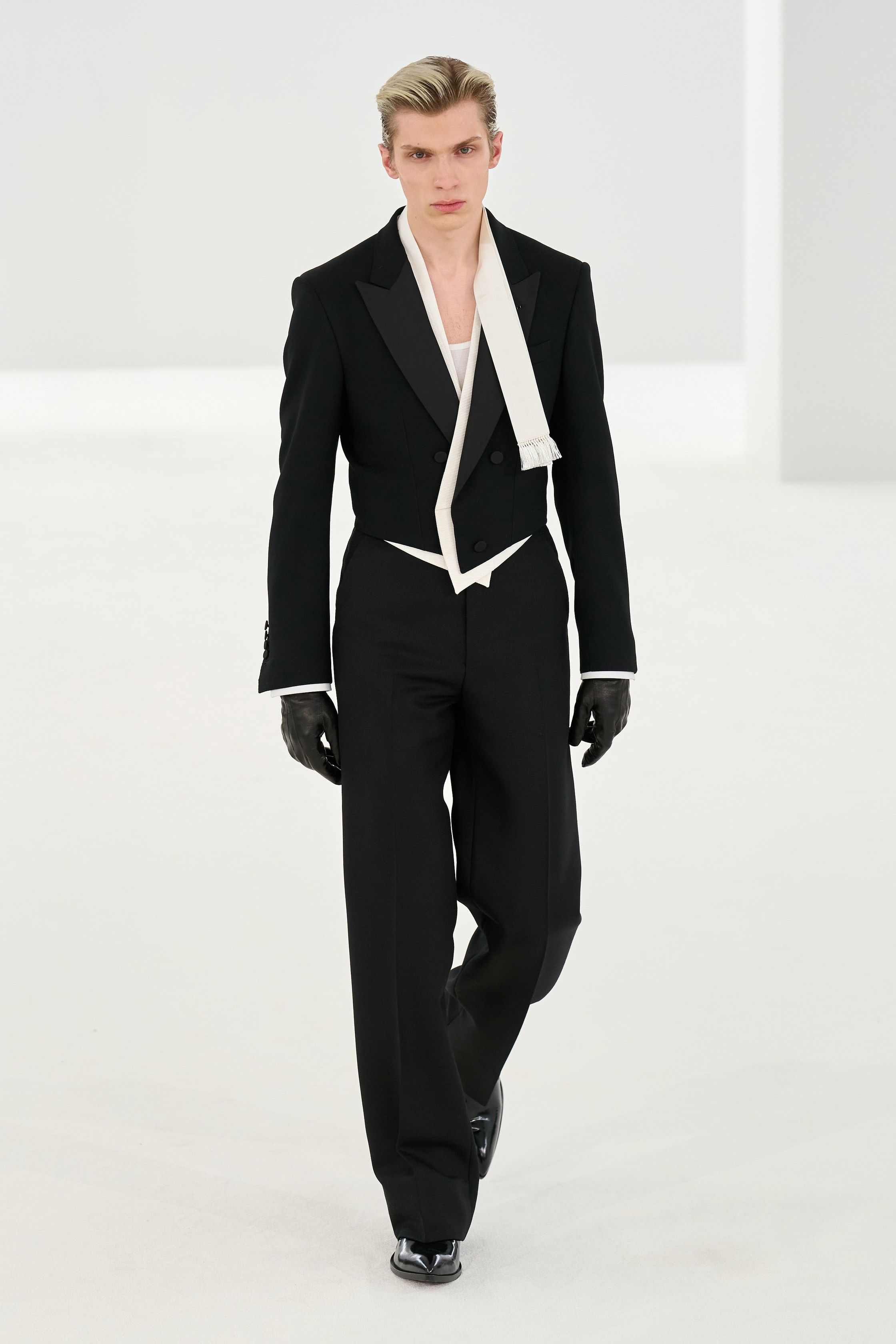 Tom Ford 2026秋冬系列回归品牌标志性的性感极简主义。高腰铅笔裙、透明材质层叠与利落西装展现强烈的都市魅力。黑色、棕色与金属光泽构成成熟而冷峻的色彩体系，皮革与光泽面料的运用强化性感张力。整体造型强调身体线条与权力感，展现Tom Ford一贯的夜晚都市美学-顽石频道趋势研究